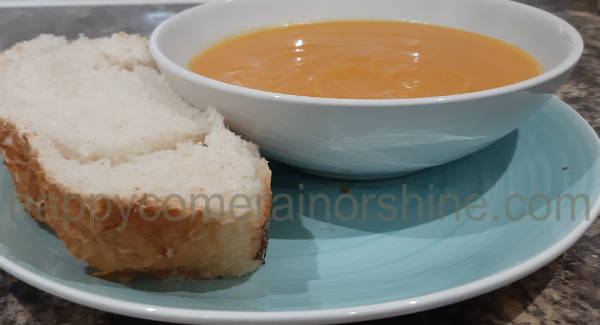 Butternut squash and sweet potato soup finished, served in a bowl and on a plate with tiger bread
